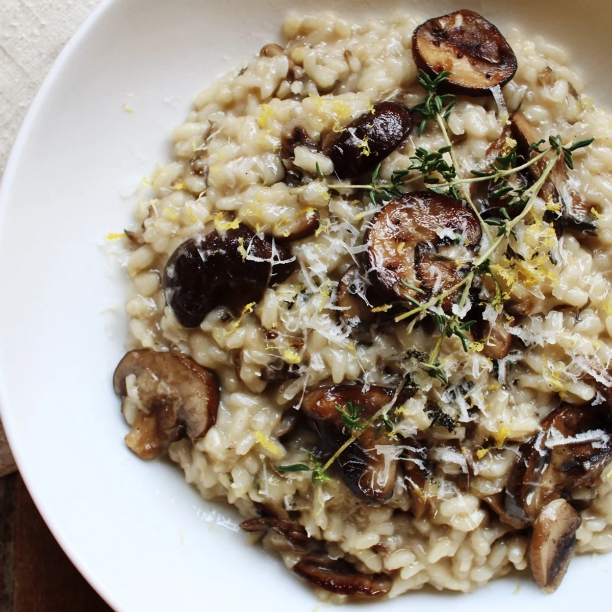 Steaming Cedar-Warm Mushroom and Thyme Risotto, a creamy dish garnished with fresh thyme and Parmesan.