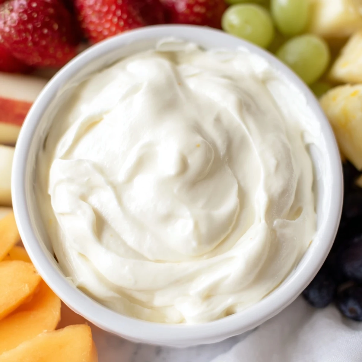Creamy cream cheese fruit dip in a bowl surrounded by colorful, vibrant fruit for dipping.