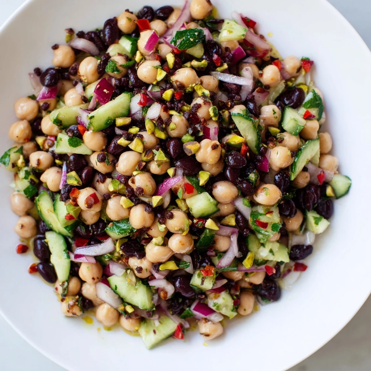 Perfectly plated Dense Bean Salad with colorful vegetables and nutty pistachios for a light lunch.