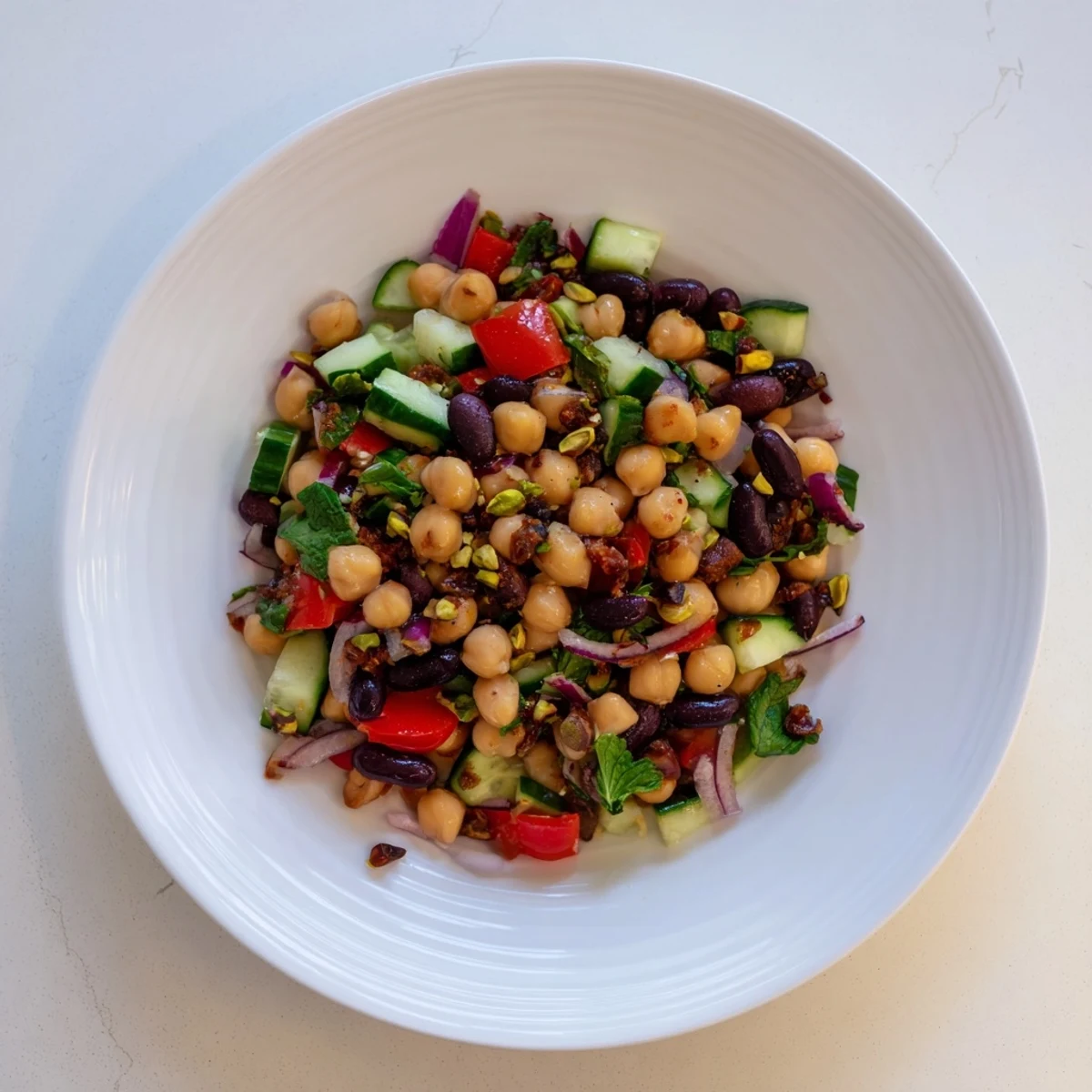 Close-up of a refreshing Dense Bean Salad with glistening olive oil and cacao nibs topping it.