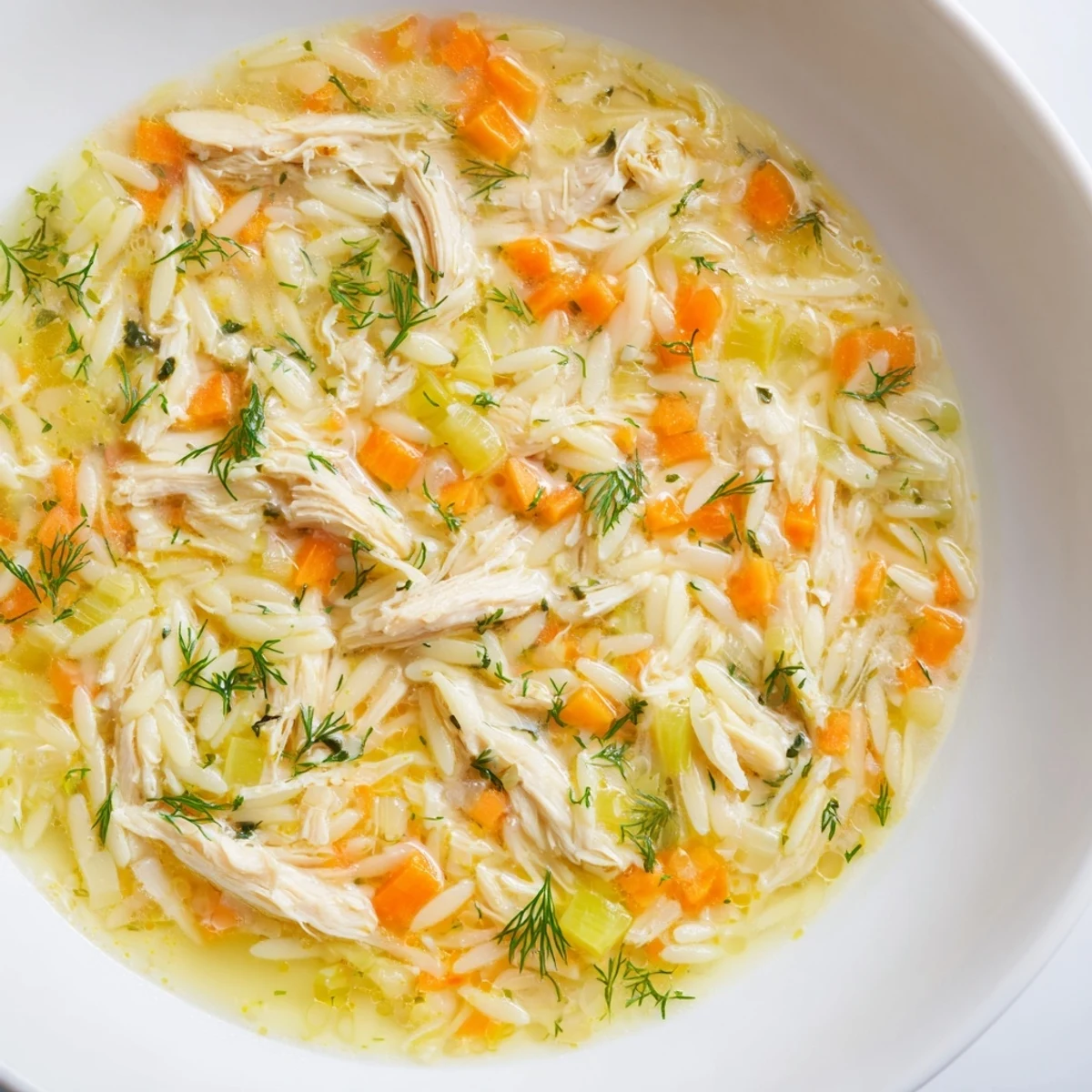 A cozy ladle of Chicken Lemon Orzo Soup garnished with parsley, with lemon wedges and steam rising nearby.