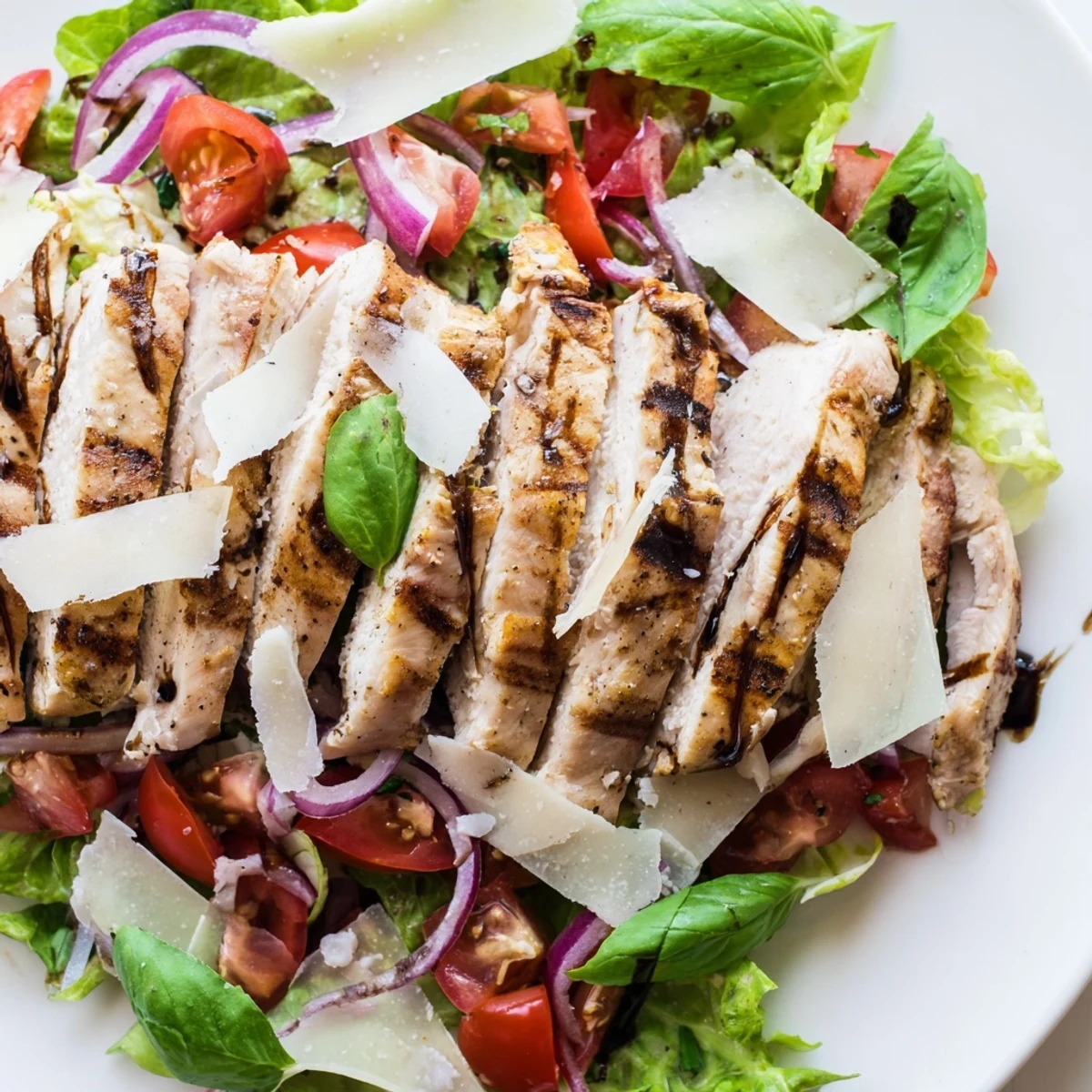 Grilled slices of Bruschetta Chicken Salad rest on vibrant mixed greens, topped with a juicy tomato and basil mixture.  