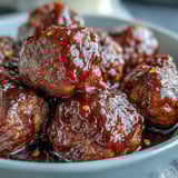 Sweet and tangy grape jelly and chili sauce meatballs simmering in a rich, glossy sauce inside the slow cooker.