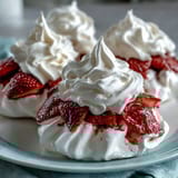 Crisp meringue nests topped with fluffy whipped cream and juicy strawberries, a light and elegant dessert for spring.