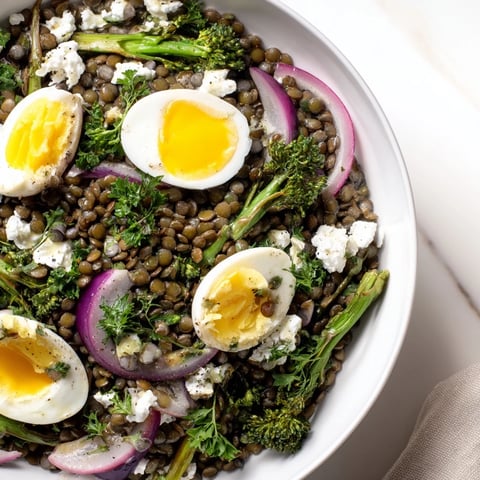 Savory French Lentil Salad With Broccolini and Soft-Cooked Eggs, topped with crumbled goat cheese and cracked black pepper.