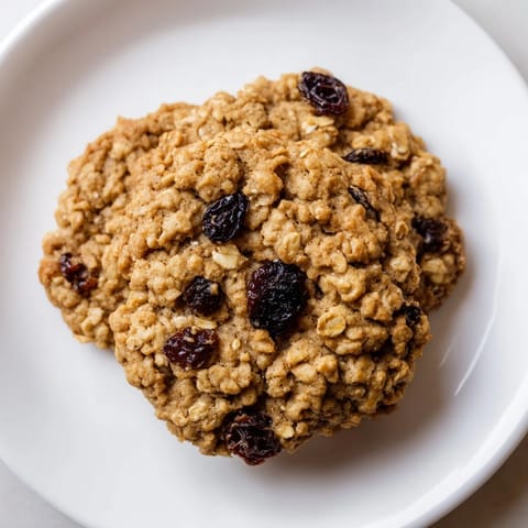 Warm, golden-brown chewy oatmeal raisin cookies, boasting plump raisins after baking to perfection.