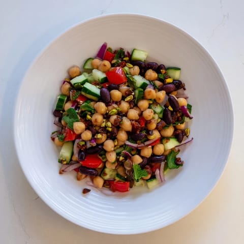 Close-up of a refreshing Dense Bean Salad with glistening olive oil and cacao nibs topping it.