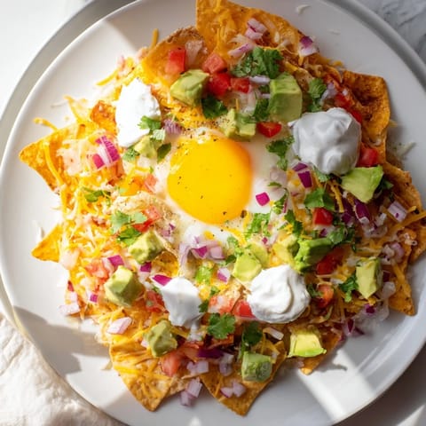 Melting cheddar and Monterey Jack cover savory Egg-Topped Breakfast Nachos with fresh salsa and avocado.