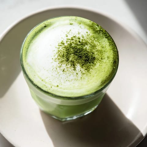 This beautiful matcha latte features a cloud of cold foam, perfect for a refreshing afternoon beverage.