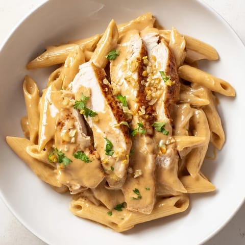 Savory Honey Chipotle Chicken Pasta served on a white plate, featuring al dente penne tossed in a glossy, sweet and smoky sauce alongside sliced, golden-brown chicken.