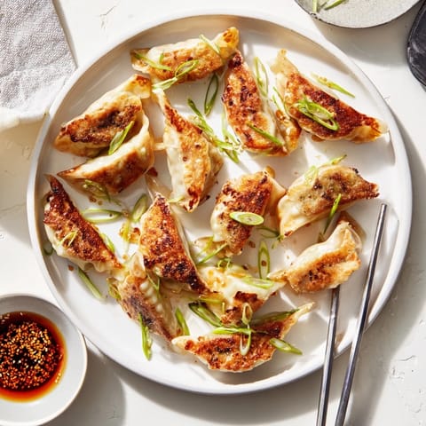 A close-up of these smashed gyozas reveals their golden edges and tender steamed wrappers, served with a dipping sauce.