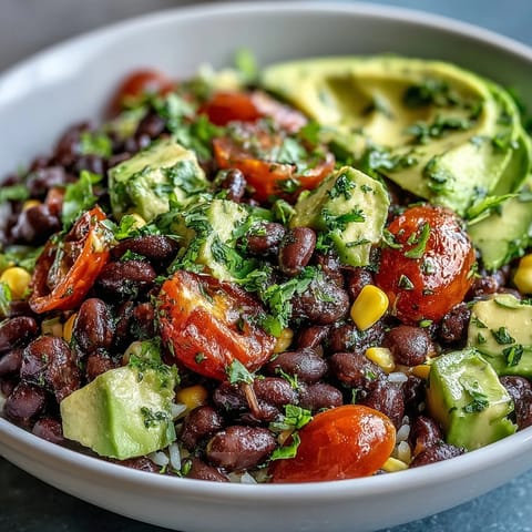 Colorful Black Bean and Veggie Bowl features seasoned black beans, sweet corn, diced avocado, and red onion, served fresh with a glistening lime vinaigrette for a quick vegan dinner.
