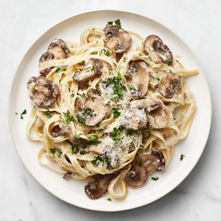 Freshly chopped parsley and grated Parmesan garnish this Creamy Mushroom Alfredo, highlighting its luscious, creamy texture and golden sautéed mushrooms.