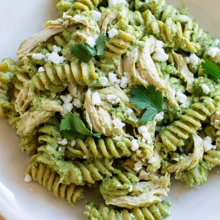 Tangy Greek yogurt sauce coats rotini and shredded chicken in this Cilantro Lime Chicken Pasta, ready to be served with crumbled cotija.