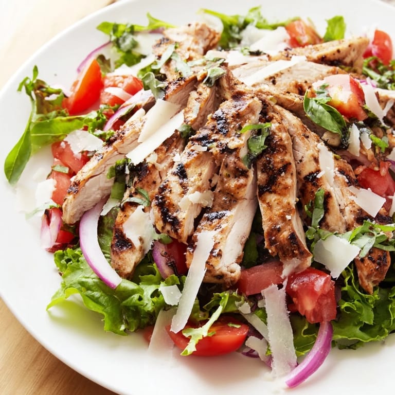 A plate of Bruschetta Chicken Salad showcases tender chicken, fresh greens, and a zesty tomato-basil mixture.