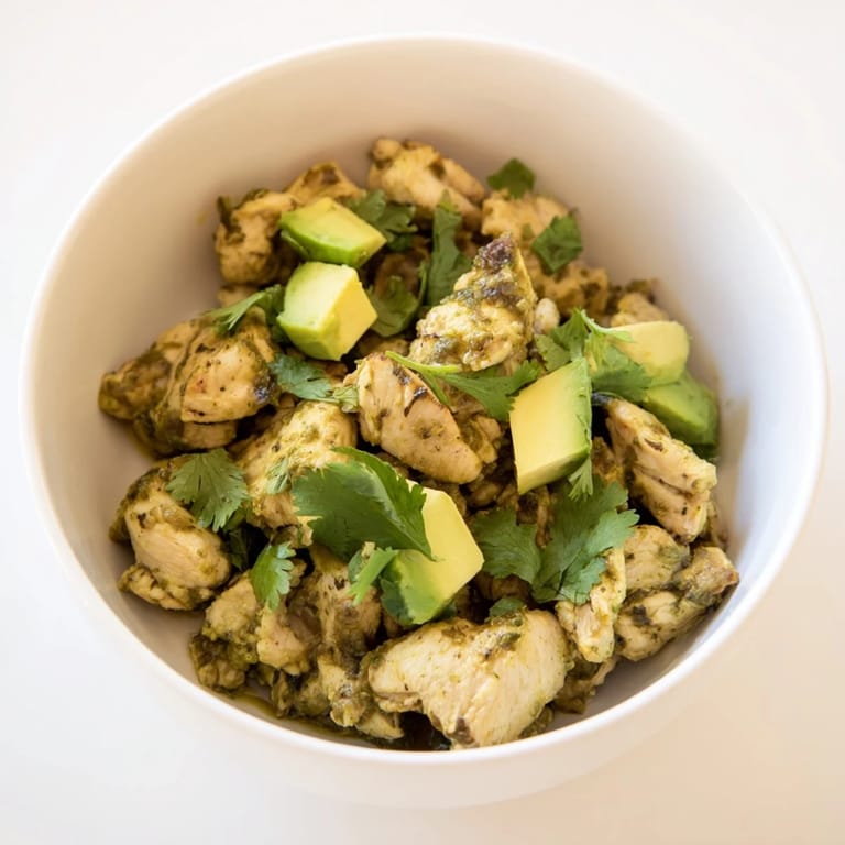 A bowl of homemade Chicken Chili Verde simmered with charred tomatillos and peppers, topped with diced avocado and sliced radishes for crunch.
