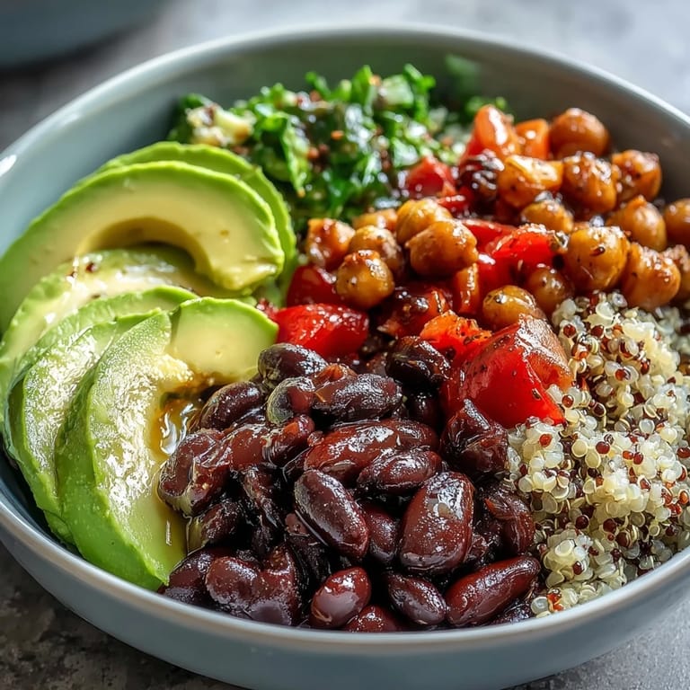 Diced red bell pepper, cucumber, and mixed greens top this wholesome Three-Bean Power Bowl, served alongside creamy avocado slices for a hearty lunch.
