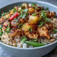Coconut Pineapple Chicken Rice Bowls with tender chicken, sweet pineapple, and coconut-infused rice, garnished with fresh cilantro and lime wedges.