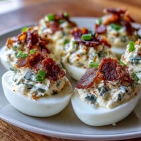 Jalapeño Popper Deviled Eggs with Cream Cheese: Spicy deviled eggs topped with bacon, jalapeños, and cheddar for a bold appetizer.